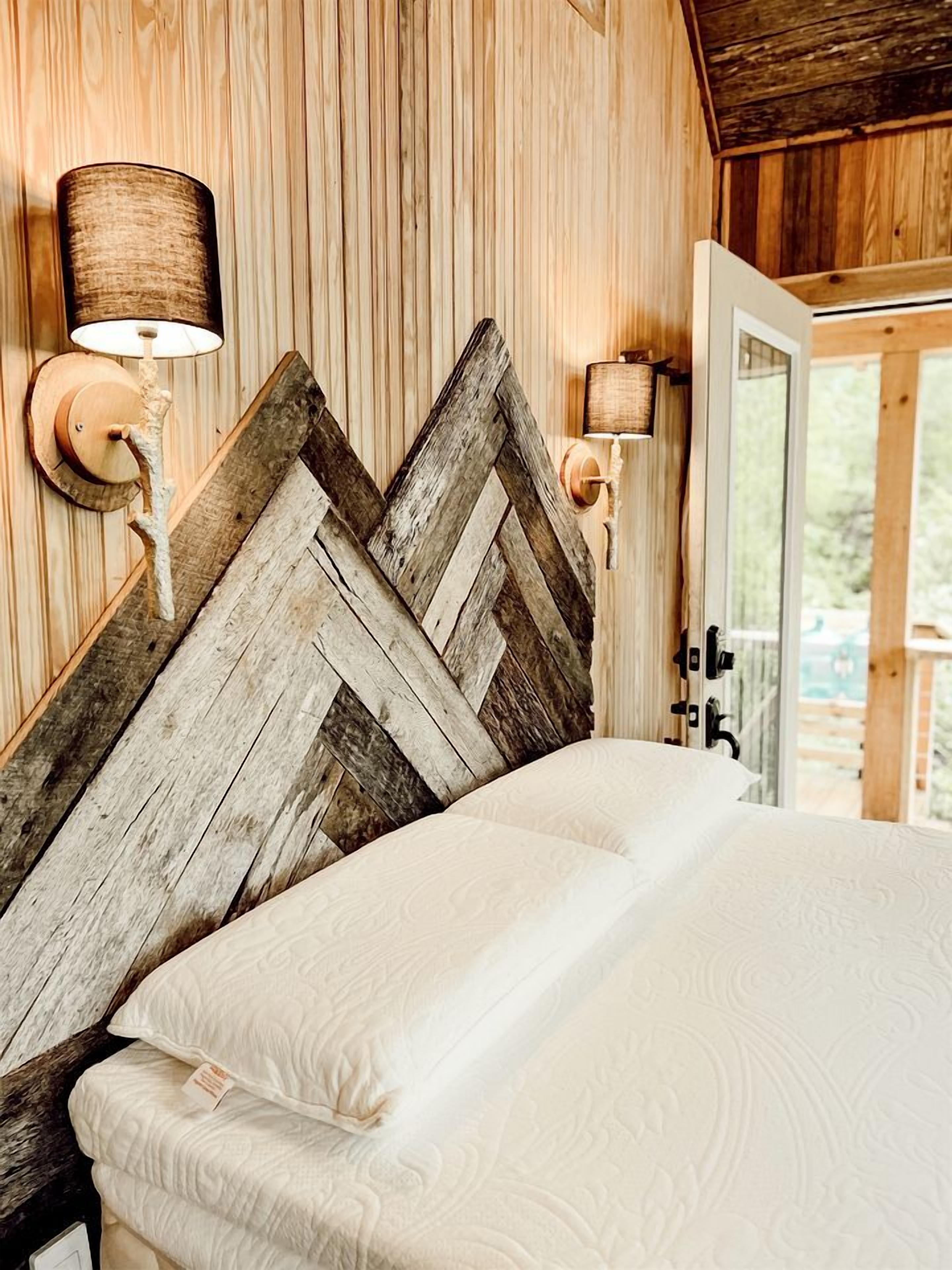 A wooden headboard with a chevron pattern, a bed with white bedding, and two wall-mounted lamps.