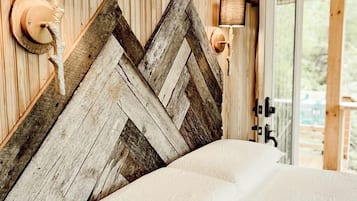 A wooden headboard with a chevron pattern, a bed with white bedding, and two wall-mounted lamps.