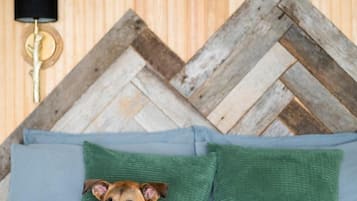 A bed with a dog, a wooden wall, and a lamp.