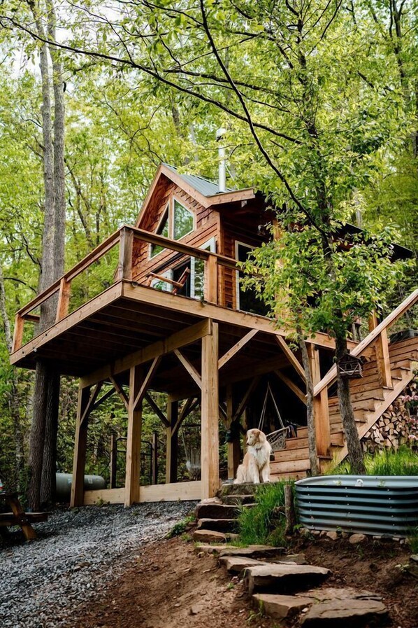 Une cabane en bois dotée d’un balcon, entourée d’arbres.