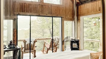 A cozy bedroom with a large bed, wooden ceiling, and a view of the outdoors.