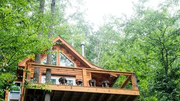Une cabane en bois dotée d’un balcon, entourée d’une forêt dense.