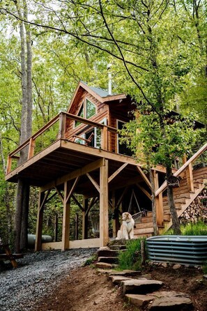 Une cabane en bois dotée d’un balcon, entourée d’arbres.