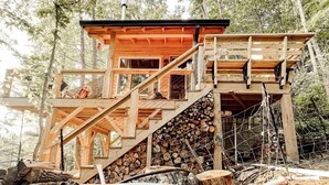 A wooden cabin with a hot tub, surrounded by trees. - Stunning Pet-Friendly Treehouse for Relaxing Glamping Retreats in North Carolina (Cantón)