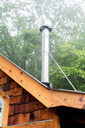 Una cabaña de madera con una chimenea de metal que sobresale del techo.