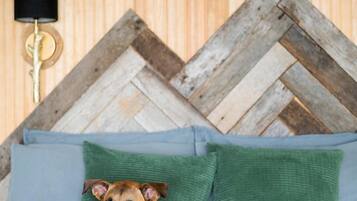A bed with a dog, a wooden wall, and a lamp.