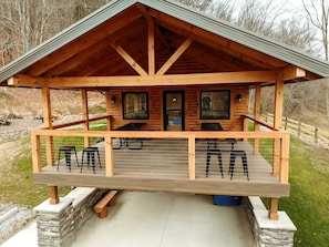 A wooden cabin with a porch, two windows, and a door.