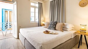 Une chambre avec un grand lit, une table de chevet avec une lampe et une vue sur le balcon extérieur.