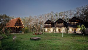 A rustic lodge with multiple wooden cabins, a grassy yard, and a picnic table. - Alpha Wolf Lodge (Tabanan)
