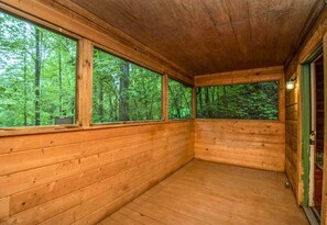 Une cabane en bois dotée de grandes fenêtres et d’un plancher en bois.