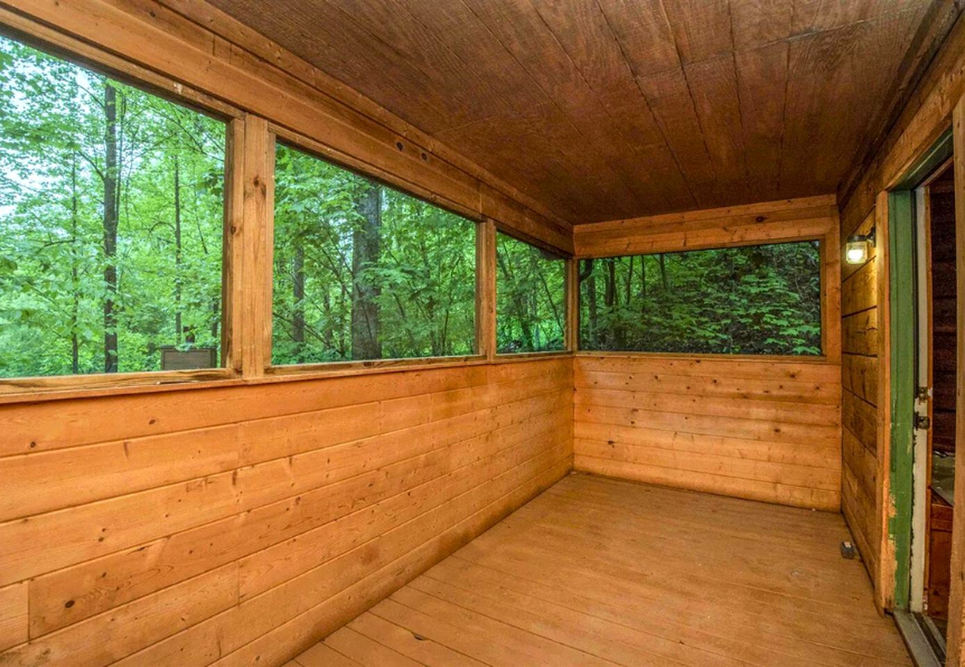 A wooden cabin with large windows and a wooden floor.