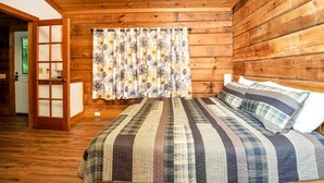 A wooden-paneled room with a bed, curtains, and a door.