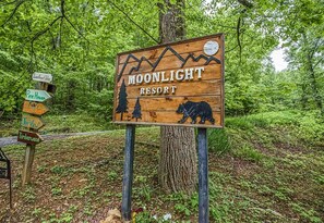 Een houten bordje voor Moonlight Resort met pijlen en een tekening van een beer.