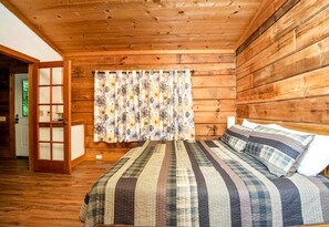 Una habitación con paneles de madera, una cama, cortinas y una puerta.