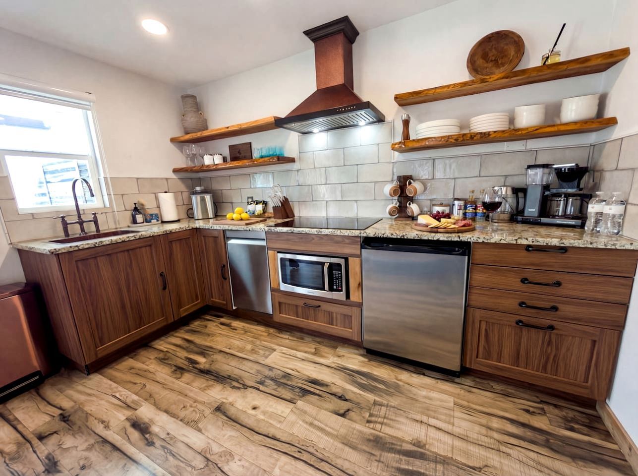 Una cocina con gabinetes de madera, lavavajillas de acero inoxidable, microondas y horno empotrado.