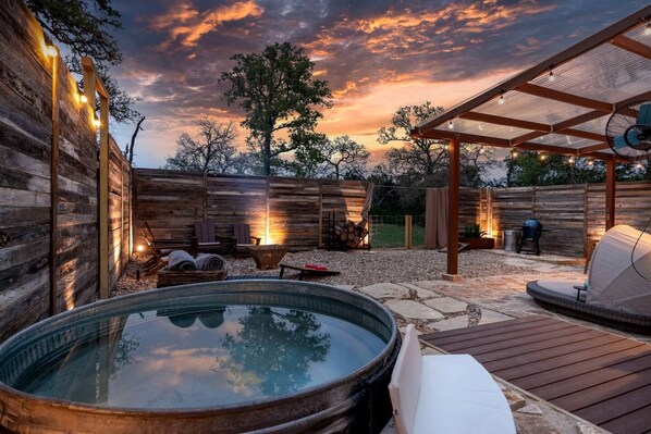 Un jacuzzi, asientos al aire libre y una pérgola con luces colgantes.
