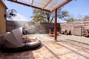 Un espacio al aire libre techado con una mesa redonda, sillas y un ventilador.