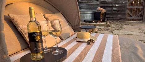 Una carpa con una botella de vino blanco y dos copas sobre una toalla a rayas.