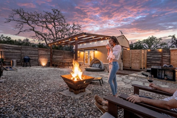 A backyard with a fire pit, outdoor seating, and a wooden pergola.