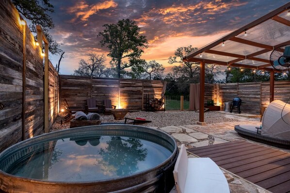 Un jacuzzi, asientos al aire libre y una pérgola con luces colgantes.