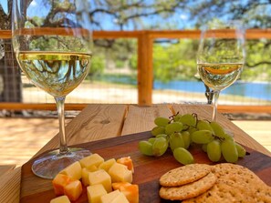 Une table en bois sur laquelle on a disposé une planche à fromages, des raisins, des crackers et deux verres de vin blanc.