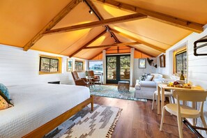 Une pièce confortable et bien éclairée, avec un lit, un coin salon et une table à manger.