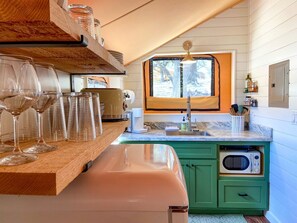 Une cuisine avec un plan de travail en bois, un évier, un four à micro-ondes et une fenêtre donnant sur des arbres.