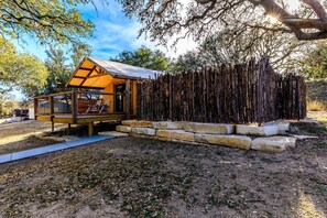 Une cabane en bois dotée d’une terrasse et d’un porche couvert, entourée d’un paysage naturel.