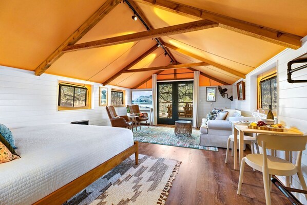Une pièce confortable et bien éclairée, avec un lit, un coin salon et une table à manger.