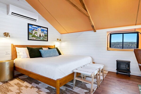 Une chambre à coucher avec un lit en bois, une petite table, une fenêtre donnant sur un beau paysage et un radiateur.