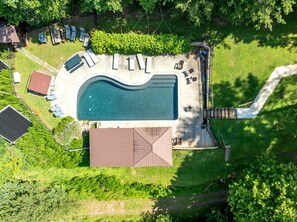 An aerial view of a residential property with a swimming pool, deck, and lounge chairs.