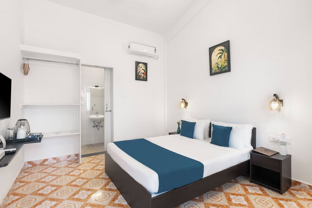 A hotel room with a bed, bedside tables, a desk with a coffee maker, a wardrobe, and a bathroom.