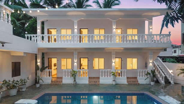 Un immeuble de deux étages doté d’une piscine, de balcons et de plantes en pot.