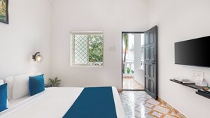 Une chambre d’hôtel avec un lit, une télévision, une fenêtre et une porte donnant sur un balcon.