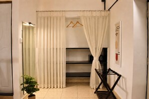 A room with a bed, a hanging clothes rack, a radiator, and a potted plant. - 8fold by LaRiSa Siolim (Siolim)