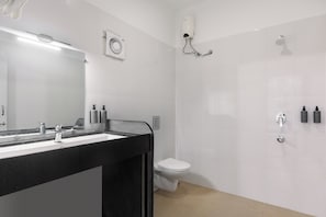 Un baño moderno con un lavabo negro, inodoro blanco y zona de ducha.