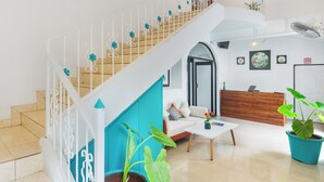 Un espace d’accueil moderne comprenant un escalier, un comptoir d’accueil, un canapé et une table basse.