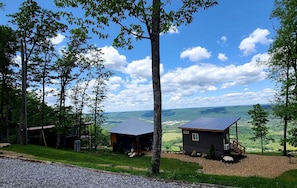 Una cabaña con techo de metal, rodeada de árboles y con vistas a un valle.