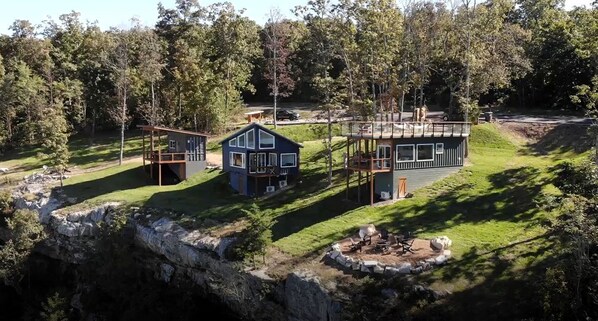 A modern cabin with a deck, a fire pit, and a stone retaining wall. - Incredible Container with Rooftop and Beautiful Sunset Views in Georgia (Rising Fawn)