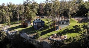 A modern cabin with a deck, a fire pit, and a stone retaining wall.