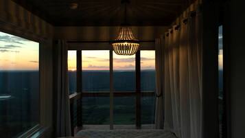 Une pièce dotée d’une grande fenêtre, d’un lit et d’un luminaire suspendu.