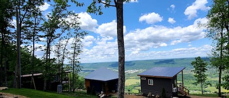 Una cabaña con techo de metal, rodeada de árboles y con vistas a un valle.