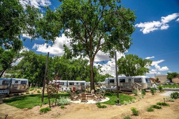 A campground with RVs, a fire pit area, and trees.