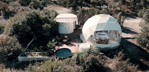 A geodesic dome structure with a circular pool and two cylindrical water tanks.