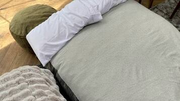 Een bed met een grijze matras, witte kussens, een groen kussen en een zachte deken.