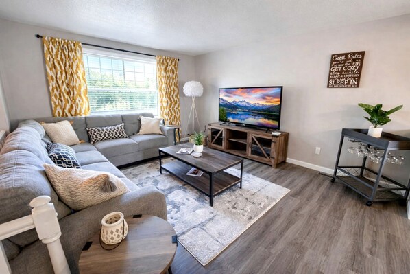 A living room with a sofa, coffee table, TV, and a wall-mounted sign.