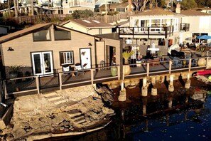 A coastal house with a wooden deck, a small porch, and a view of the water.