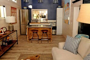 Un espacio habitable compacto con kitchenette, un sofá y una mesita de centro.