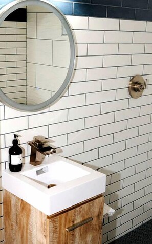 A bathroom with a white sink, wooden cabinet, and a mirror.