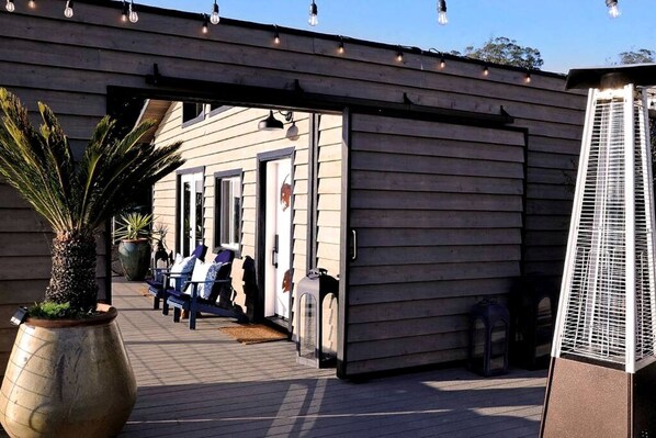 A wooden building with a covered walkway, outdoor seating, and a large potted plant.